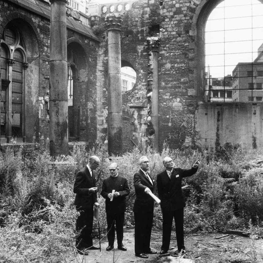 Black and white image (L-R) Architect Patrick Horsebrugh, Canon C B Mortlock, Dr Robert Davidson and Marshall Sisson standing in dark suits in the middle of the ruins of St Mary Aldermanbury in London in July 1964