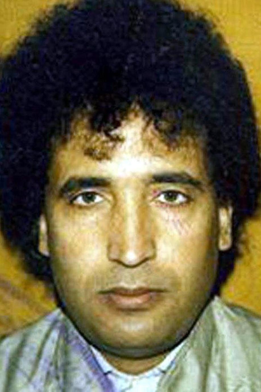 Abdulbasset Al Megrahi looking straight at the camera. He has black curly hair and there is a yellow background.