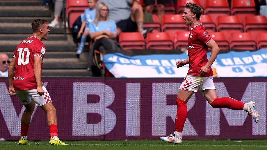 Two Bristol City players run towards each other in celebration after taking the lead against Coventry City at Ashton Gate