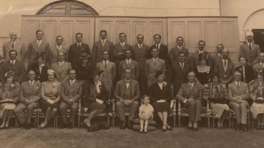 Black-and-white photo of colonial officials, with little boy at the front dressed in white, who is Susannah's father