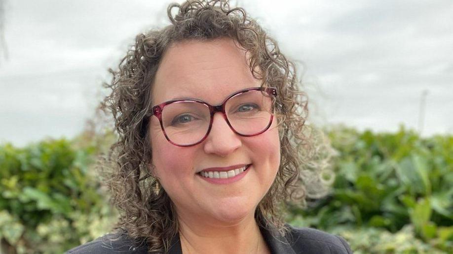 A curly-haired woman wearing glasses