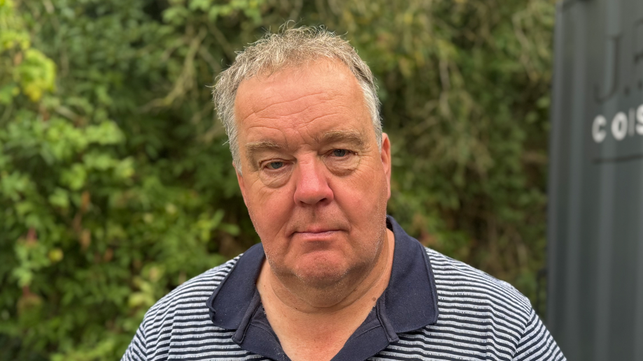 A head shot of David Ruffles. He is wearing a navy and white striped polo shirt. He is looking directly into the camera.