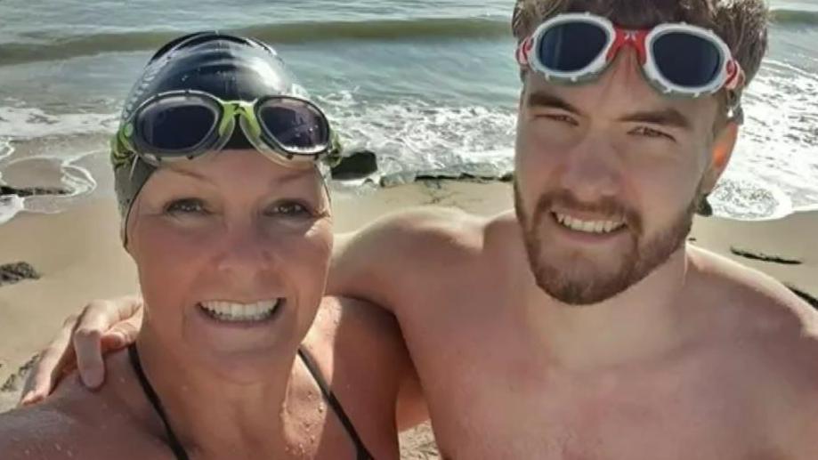 Tracy and Connor Clark on a beach in swimming goggles