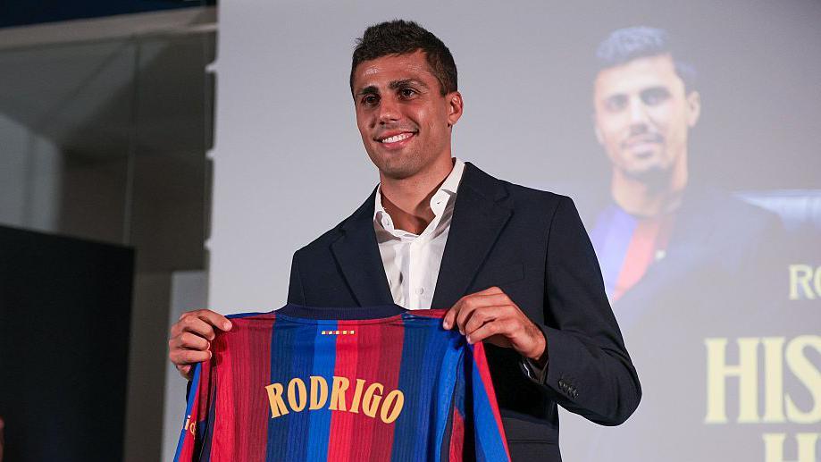 Rodri holding up a Barcelona shirt.