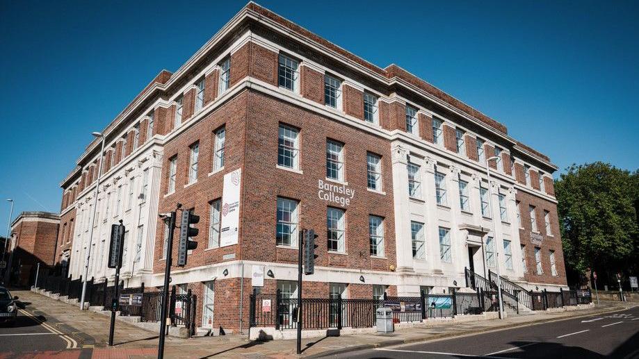 A large four-storey, art-deco building in a classic style, on the corner of two streets.   