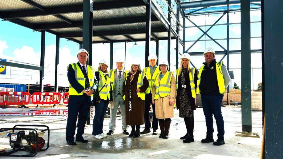 A group of eight people wearing high-vis jackets and white helmets standing in the external structure of the cinema next to Lidl.