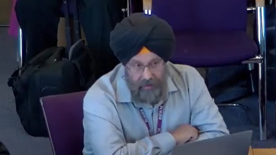 Kashmir Singh, sitting with crossed arms, pictured at a previous council meeting. He is wearing a black turban and a blue/grey shirt and wearing a RBWM lanyard around his neck 