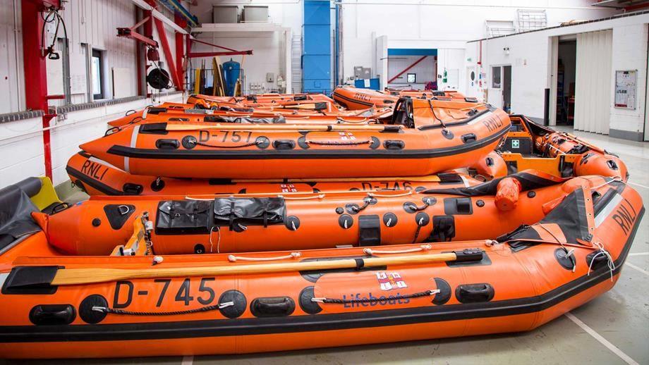 Row if orange RNLI inflatable lifeboats inside a building.