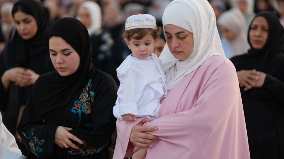 A woman holding a baby as she prays