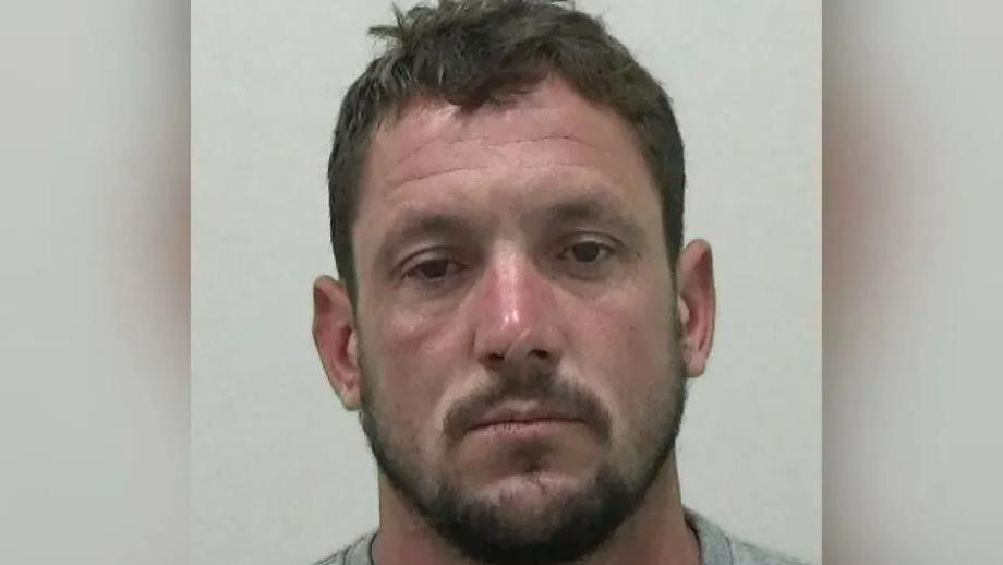 A mugshot of Darren Jacques, who has brown hair and facial hair.