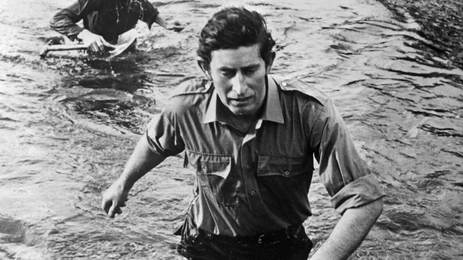 King Charles III back when he was the Prince of Wales in 1974 wades through waist-deep water during training at the Commando Training Centre in Devon.