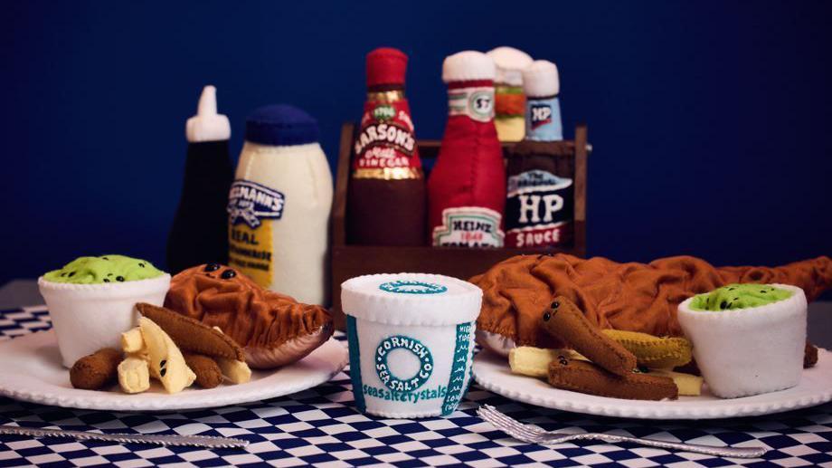 A hand stitched meal of fish and chips with condiments 