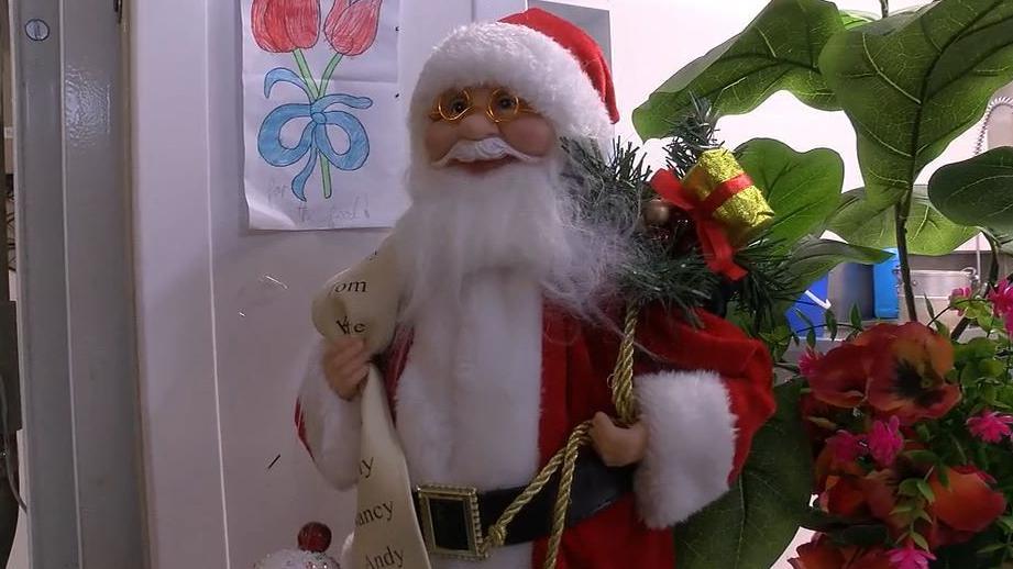 A Santa decoration holding a name list and a sack of presents.