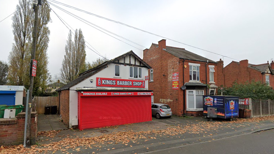 A white building with red shutters next to a red brick building