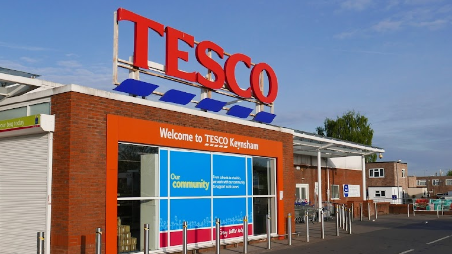 The exterior of Tesco superstore in Keynsham. It is a close up of the building which is red brick and says 'Welcome to Tesco Keynsham'.