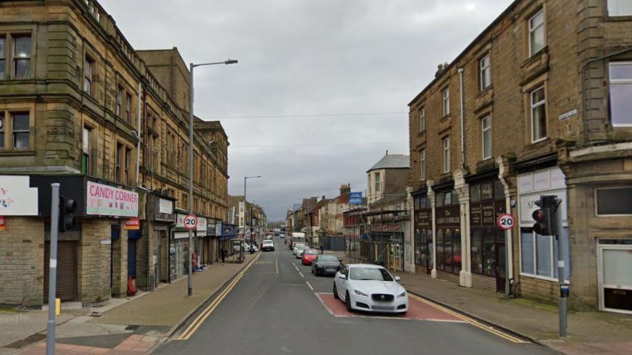 The traffic light junction of Regent Road in Morecambe showing a number of shops and cars waiting at the lights on a cloudy day.