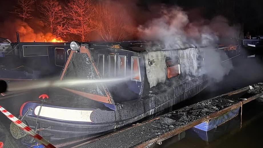 A smoking canal boat is hosed down 