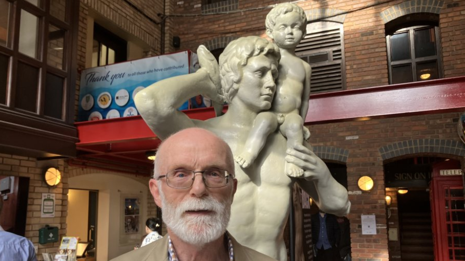 Son of sculptor in front of statue