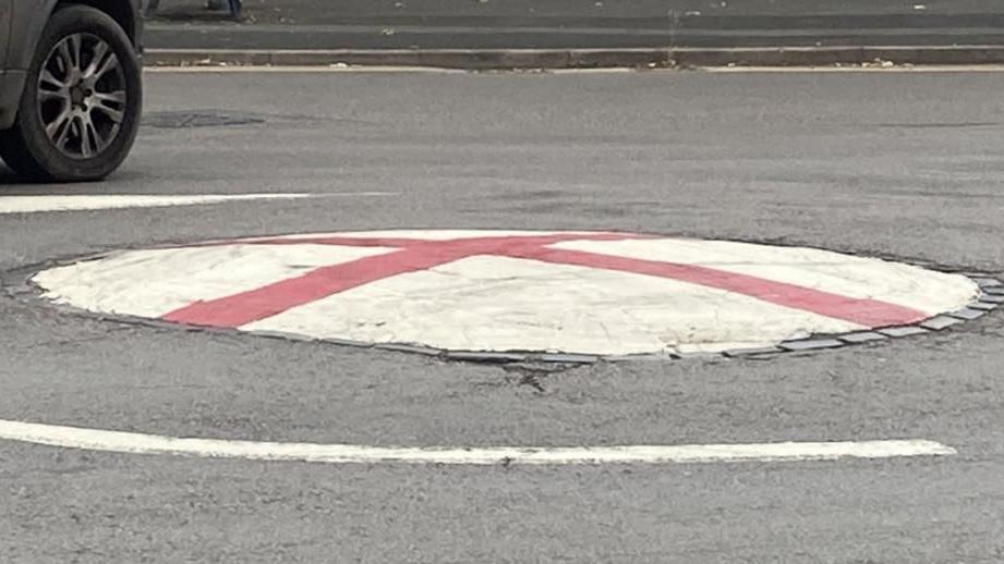 A mini roundabout covered with paint in the style of the Cross of St George flag