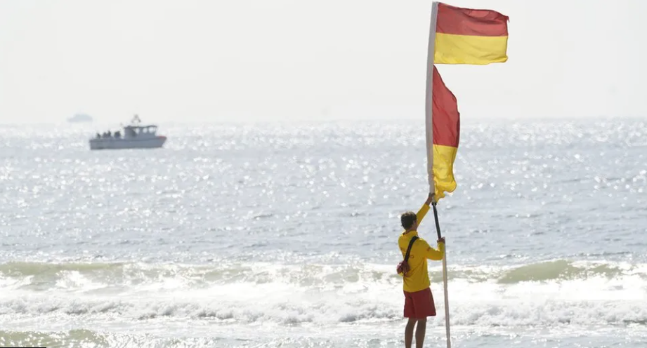 A lifeguard erecting a patrol flag at the seashore