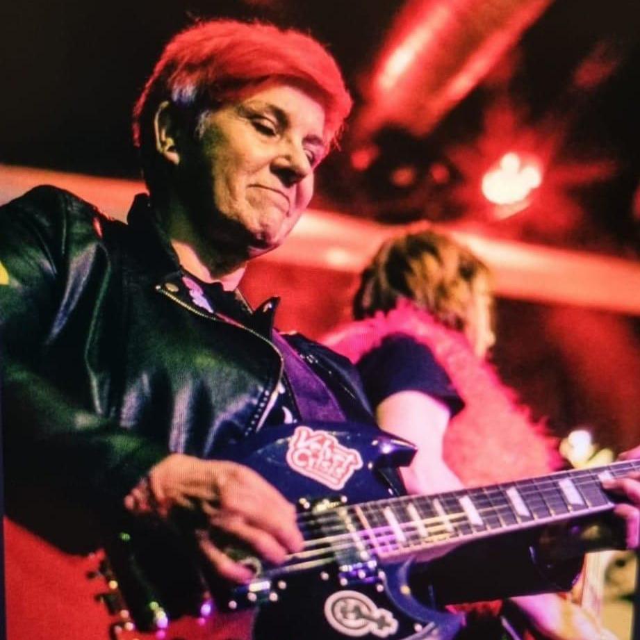 Steph performs guitar on stage with her band Velvet Crisis