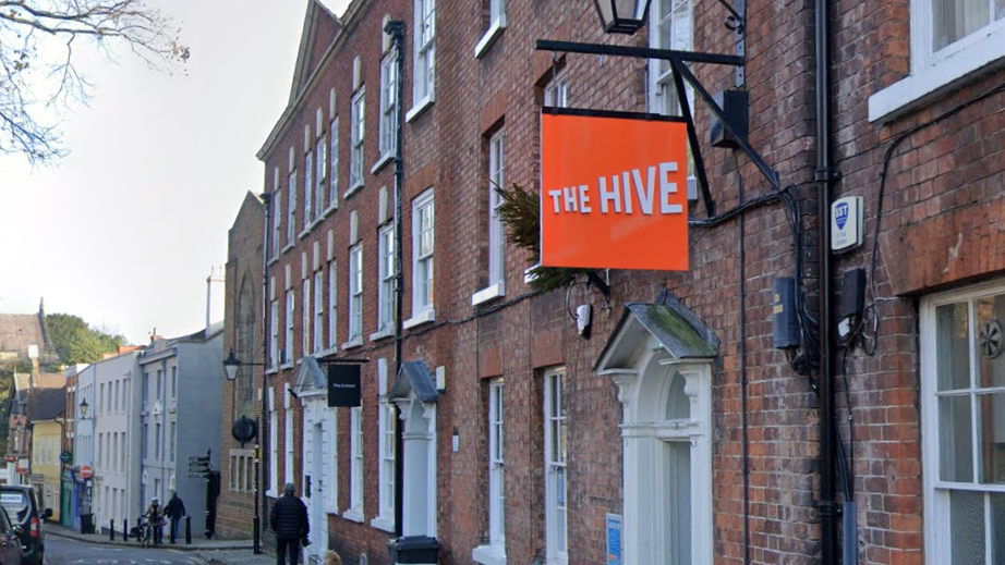 An orange Hive sign hanging about a door on a terraced street