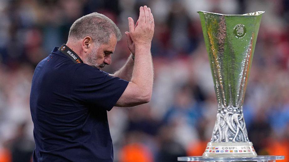 Ange Postecoglou applauds fans as he walks past the Europa League trophy