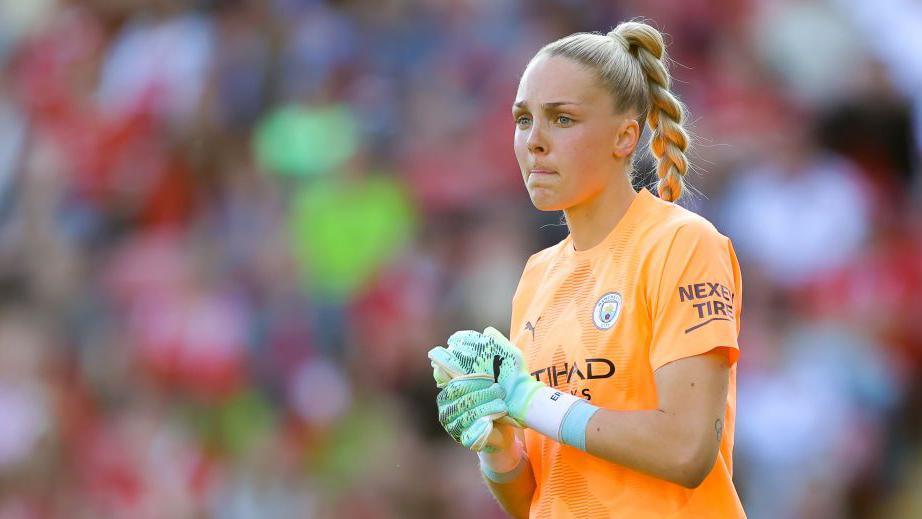 Roebuck looks out on the pitch with her hands clasped