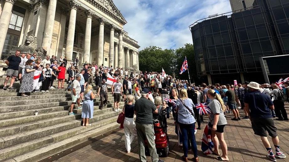 Hundreds of protesters standing on the wide stone steps of Portsmouth's Guildhall