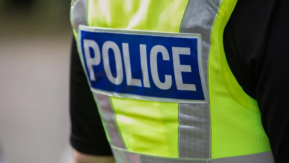 A close-up of a police officer wearing a hi-vis jacket with the word 'police' emblazoned on the back.