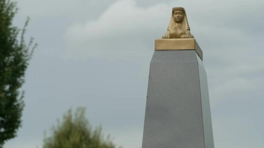 A golden sphinx on top of a granite plinth