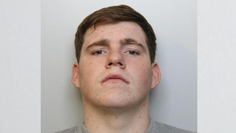 Custody image of James Doherty. He has brown hair and is wearing a grey top. He is looking directly into the camera.