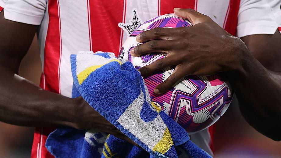 A close-up of Brentford's Michael Kayode drying the ball with a towel