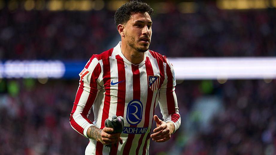 Jose Gimenez of Atletico Madrid takes a pigeon of the pitch during the La Liga match between Atletico de Madrid and Real Sociedad 