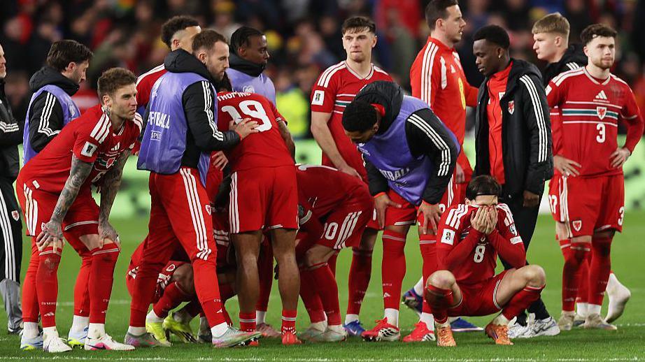 Wales players are dejected in a group shot on the halfway line during the penalty shoot-out