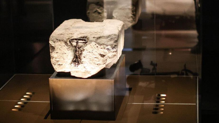 The Stone of Destiny sits on a raised platform and is lit by surrounding lights. It is concealed behind a glass case.