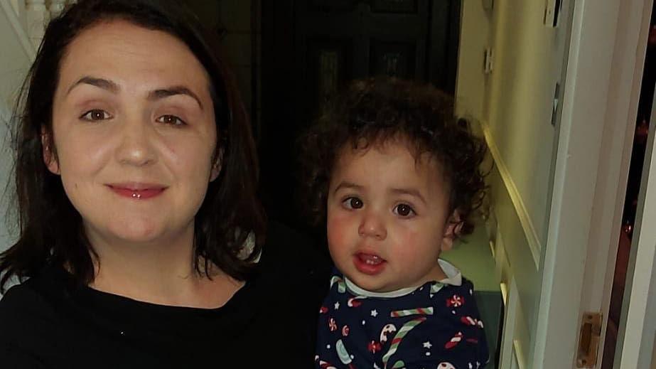 A close-up of a woman and a child. The woman is wearing a dark top and has dark hair.