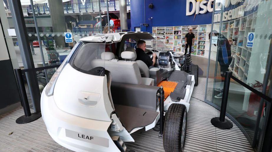 The Nissan LEAF car cross-section being driven through the Discovery Museum's front door.