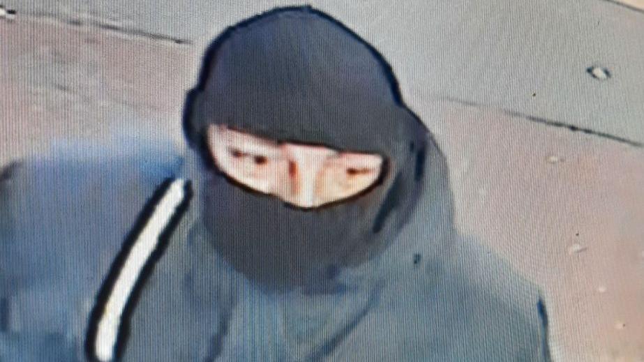 A CCTV image of a man wearing a black balaclava and a dark coloured jacket.