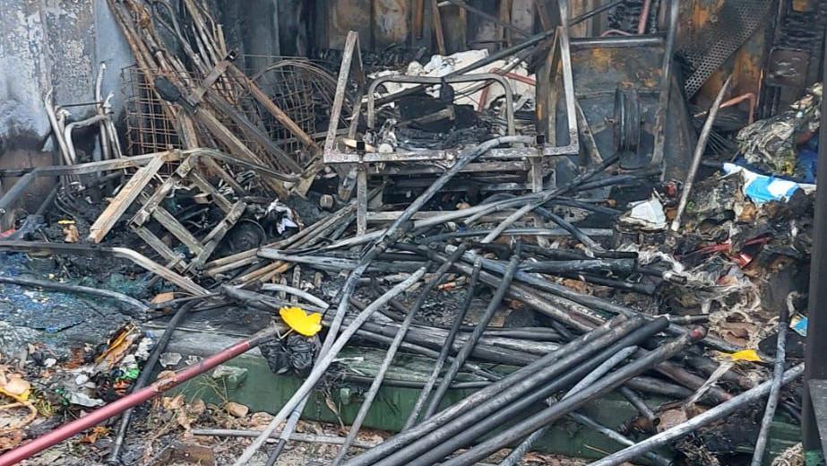 Burnt and damaged items, inside a storage container, on the floor, all charred and damaged. 