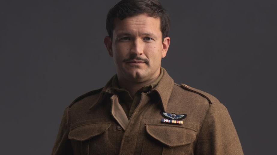 Actor Corin Silva dressed in mock wartime uniform for his part in SAS Rogue Heroes. He has short dark hair and a moustache