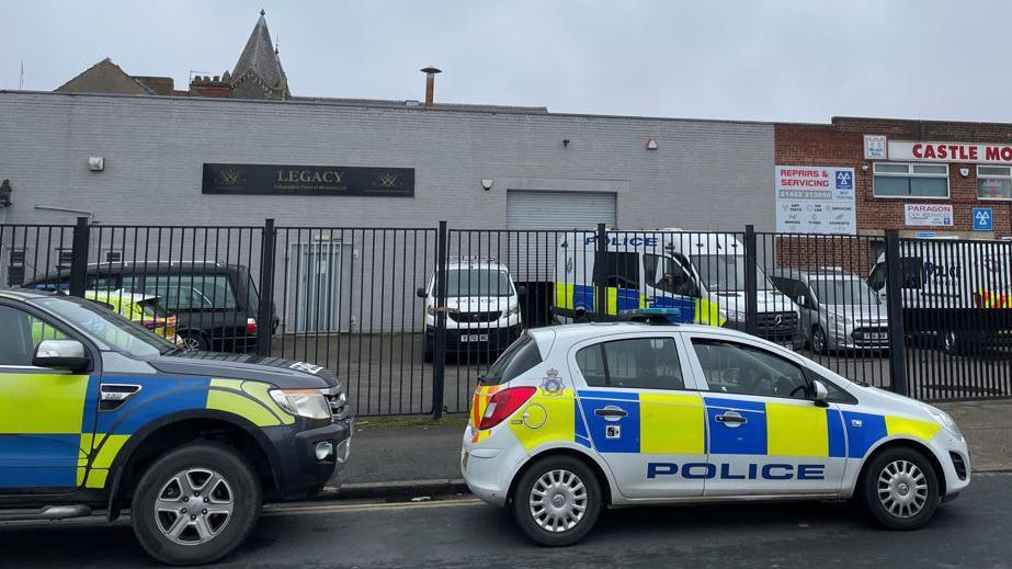 Police vehicles parked in front of a singe-storey funeral home 