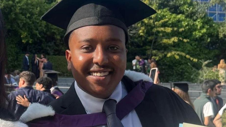 Abubaker Elmubarak wearing a cap and gown on his graduation day