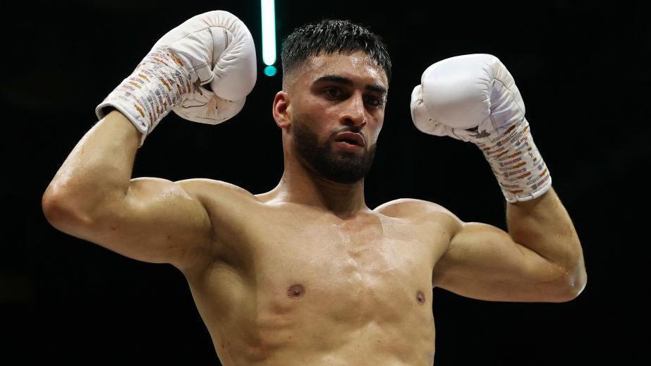 Adam Azim holds up his boxing gloves celebrating