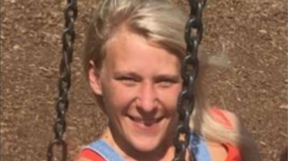 A smiling Charlotte Tetley relaxes on a swing, her blonde hair blowing in the wind