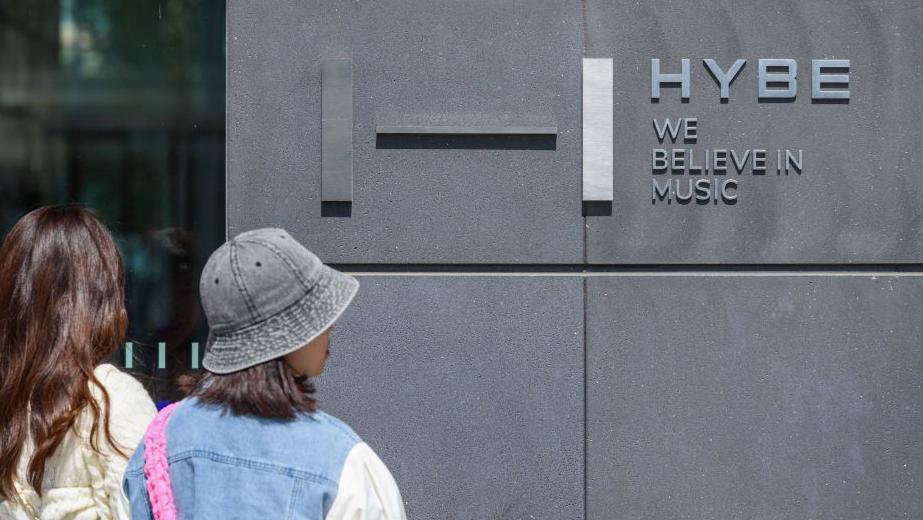  People walk past the Hybe Building in Seoul.