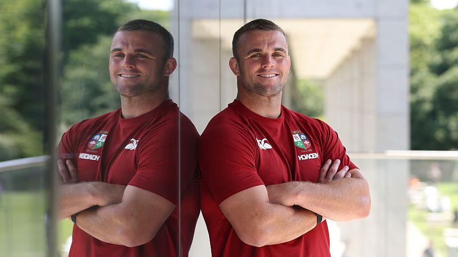 Ben Earl poses with his arms crossed while wearing British and Irish Lions training gear