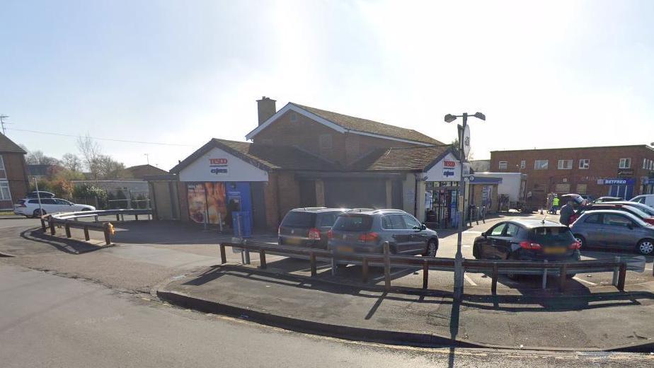 A Tesco Express store with cars parked outside.