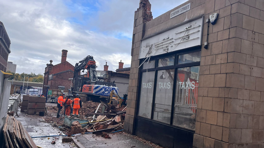 Workmen standing among the remains if a demolished building