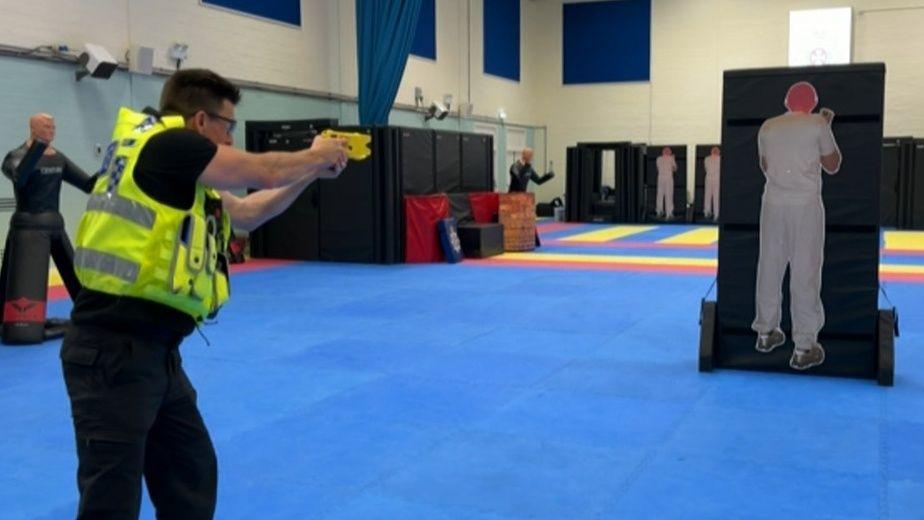 A police officer firing a taster into a target